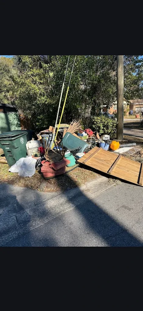 Before photo of a curbside pile of junk including an old fence gate