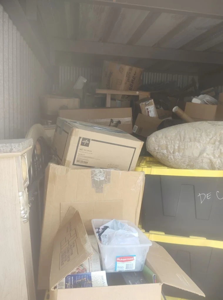 Before photo of a storage unit packed with boxes and furniture