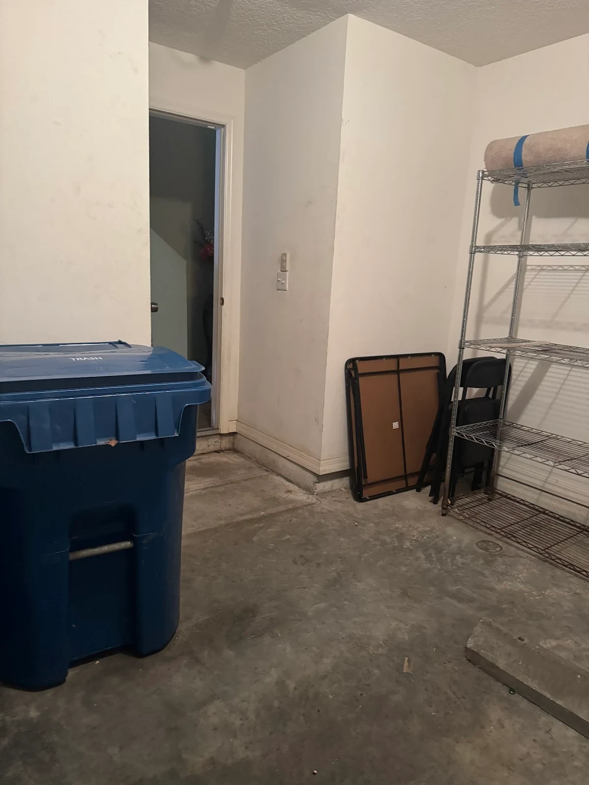 Same room cleared out with only a trash bin and shelving left